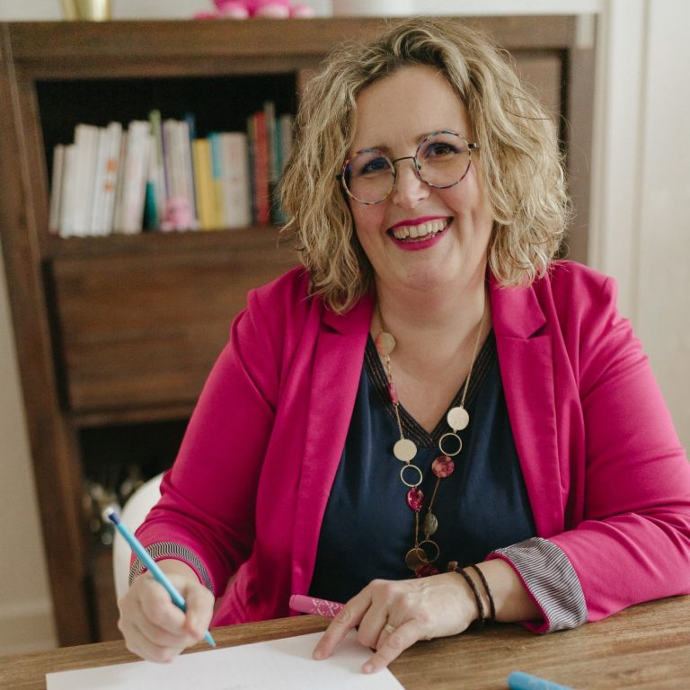 Une photo de Delphine Berque souriante en train d'écrire à un bureau